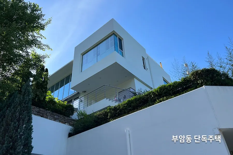 산줄기를 마주한 백색 외관의 코너 통유리 단독주택 전경