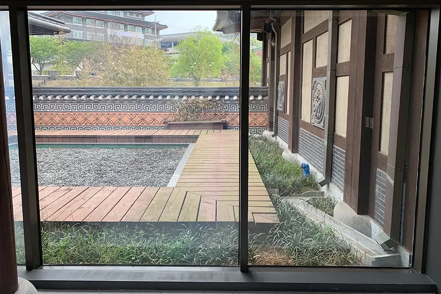 시공 전 회랑 통유리, 마당과 건너편 회랑이 선명하게 비치는 상태