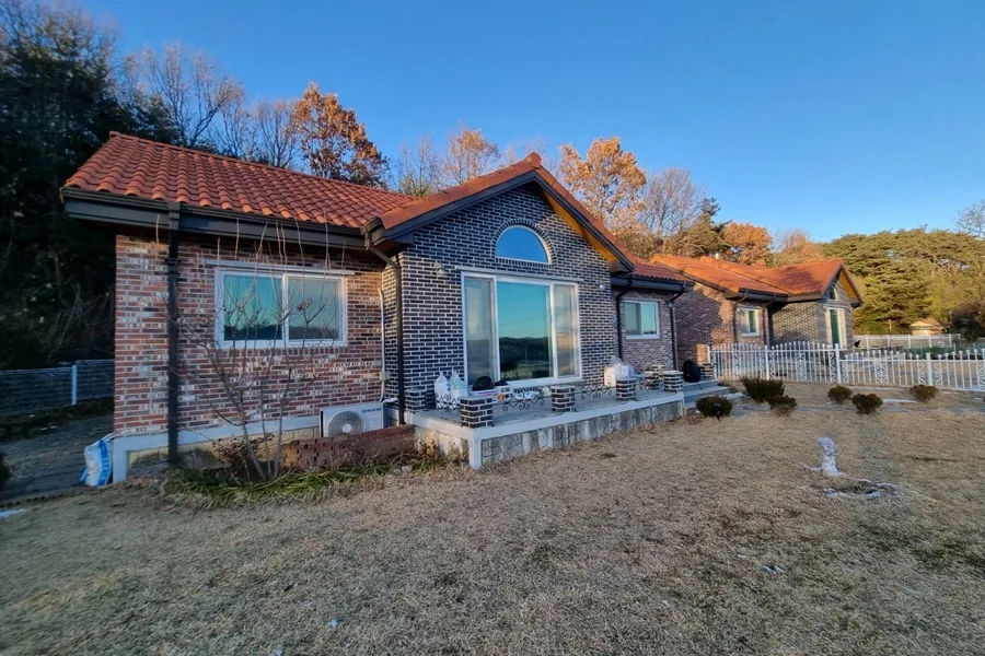 논밭과 낮은 산줄기를 마주한 전원주택 외관 전경