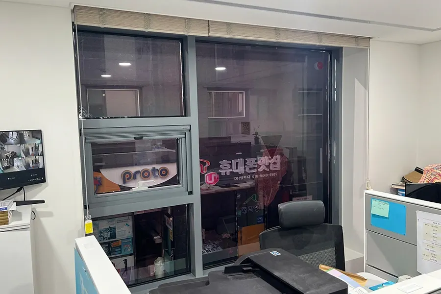 시공 전 사무공간 창, 맞은편 상가 간판과 실내가 그대로 비치는 모습