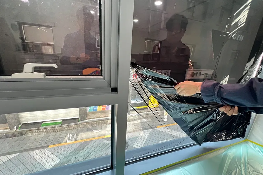 시공 기사가 창에 단열필름을 부착하는 진행 장면