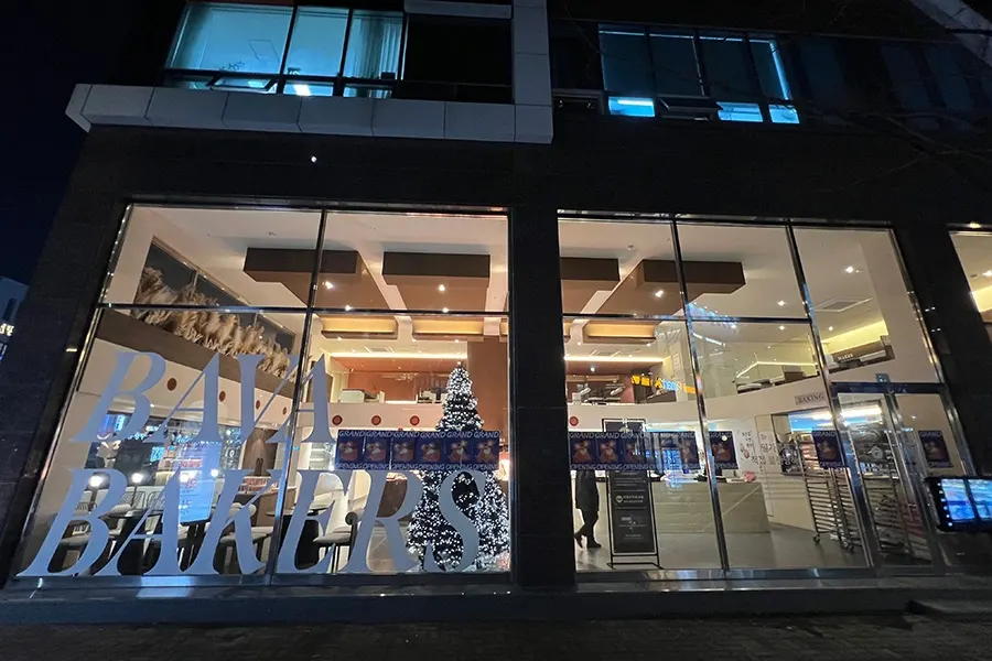 야간에 조명이 켜진 베이커리카페 대형 통유리 파사드 전경